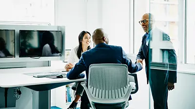 Three colleagues in business attire conversing.