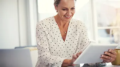 A woman smiling while using a smart tablet 